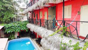 a red building with a swimming pool next to a house at Arrecife Montañita Hostal in Montañita