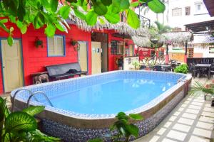 a swimming pool in front of a red house at Arrecife Montañita Hostal in Montañita