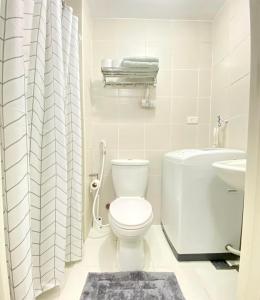 a white bathroom with a toilet and a sink at Will’s Place at Jazz Makati in Manila