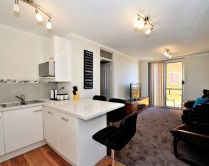 een keuken en een woonkamer met een aanrecht en stoelen bij Harbour Breeze - Central Fremantle Apartment in Fremantle