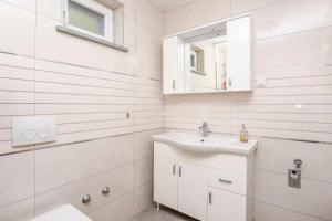 Un baño blanco con lavabo y espejo. en Apartments Mario, en Brodarica 55 fotos más