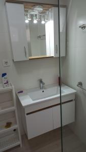 La salle de bains blanche est pourvue d'un lavabo et d'un miroir. dans l'établissement Sunny apartment, à Skopje