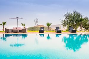 a swimming pool with chairs and an umbrella at Kasbah Ait Oumghar in Demnat