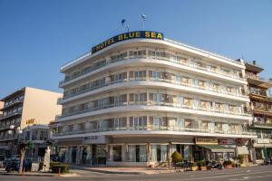 un gran edificio blanco con una señal azul de mar. en Blue Sea Hotel en Mitilene