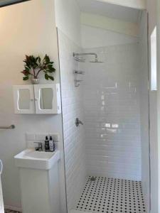 La salle de bains blanche est pourvue d'un lavabo et d'une douche. dans l'établissement Protea Loft - Romantic stay - No Load shedding, à Hilton