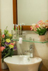 a bathroom with a sink and a mirror and flowers at Phố Seoul Homestay And Spa in Hoi An +19 photos