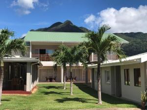a house with palm trees and a mountain in the background at Panorama Guesthouse Apartments Beau Vallon Beach in Beau Vallon