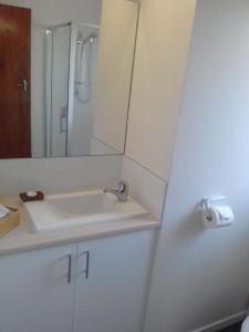 Baño blanco con lavabo y espejo en Burnie BNB With Ocean Views, en Burnie