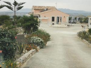 a driveway leading to a house with flowers at La valle degli dei in Eraclea Minoa