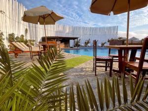 a pool with tables and chairs and an umbrella at Delfines de Chicama Hotel in Puerto Chicama