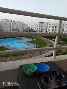 una mesa con tazones de comida en un balcón con piscina en Amwaj North coast chalet families only, en El Alamein