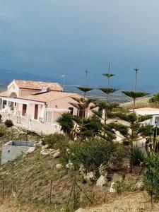a house on a hill with trees in front of the ocean at La valle degli dei in Eraclea Minoa