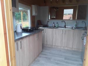 a kitchen with wooden cabinets and sinks and a window at Kempings Jūrmalnieki in Mazirbe