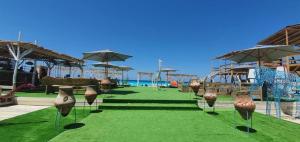 a field of green grass with vases and umbrellas at Amwaj North coast chalet families only in El Alamein