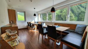 a dining room with a table and chairs and windows at Bergzeit Appartements in Warth am Arlberg