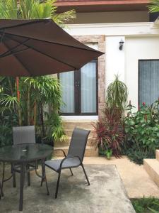 a patio with a table and chairs and an umbrella at Villas Chaba in Thong Nai Pan Yai