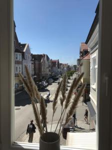 a vase with a plant in a window with a street at Alte Glaserei Travemünde in Travemünde