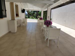 a dining room with tables and chairs and purple flowers at B&B Villa Fanizza in Porto Cesareo