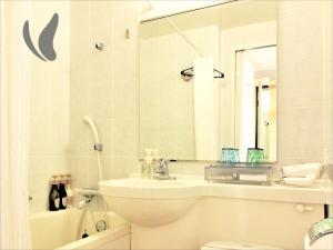 a bathroom with a sink and a toilet and a mirror at Almont Hotel Naha Omoromachi in Naha