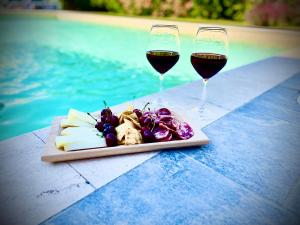 due bicchieri di vino e un piatto di cibo accanto a una piscina di B&B Le pavoncelle sarde a Flumini di Quartu