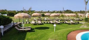 a group of chairs and umbrellas next to a pool at Samanà Bed and Breakfast in Punta Prosciutto