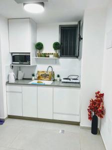 kuchnia z białymi szafkami i kuchenką mikrofalową w obiekcie Jaffa 17 - urban loft w Jerozolimie