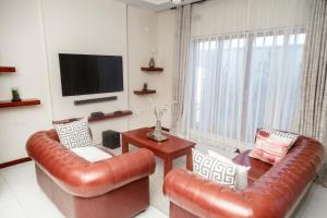 a living room with two leather chairs and a television at Grayville Apartments in Lusaka