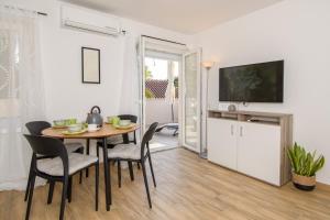 a dining room with a table and chairs and a television at Apartments & Rooms Darrer in Poreč