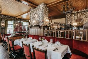 a restaurant with white tables and red chairs at Hotel Alter Muschelsaal in Büsum