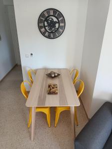uma mesa com cadeiras amarelas e um relógio na parede em Motril - Poniente Beach em Motril