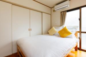 a bedroom with a white bed with yellow pillows at Naha Gajumaru Apartment Hotel 301 in Naha
