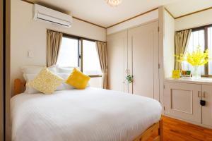 ein Schlafzimmer mit einem weißen Bett und gelben Kissen in der Unterkunft Naha Gajumaru Apartment Hotel 301 in Naha