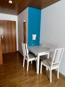 a table with two chairs and a blue wall at Pension Seliger in Meersburg
