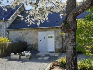 un garaje con una puerta blanca y un árbol en Le Clos Doux, en Céaux