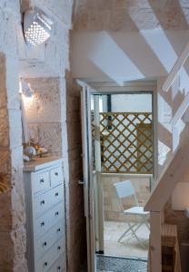 una stanza con scala, cassettiera bianca e sedia di Casa Maristella a Cisternino