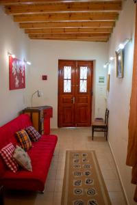 a living room with a red couch and a wooden door at Michael Apartment in Áyios Andréas Messinias