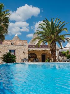 a swimming pool in front of a house with a palm tree at Trulli D'autore in Martina Franca