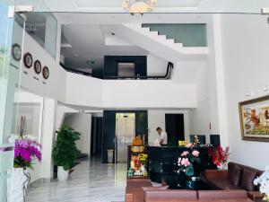 um hall de entrada com uma escada e um homem de pé no balcão em THẢO AN 2 HOTEL Huế em Thôn Lại Thê