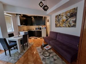 - un salon avec un canapé violet et une table dans l'établissement Apartman Veselinovic Free PARKING, à Vranje