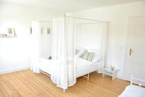 a bedroom with a white canopy bed with white curtains at frigg flats I Scandi InteriorI JugendstilI Altbau in Landshut