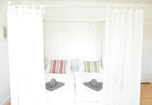 a bedroom with white curtains and a bed with two pillows at frigg flats I Scandi InteriorI JugendstilI Altbau in Landshut