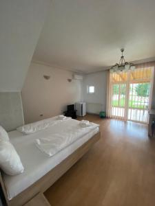 a bedroom with a large white bed and a wooden floor at Vila Hubert in Baile Felix
