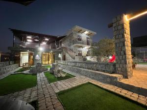 a house with a stone wall and a courtyard at night at nbz chalet Jasmine stairs in Al ‘Aqar