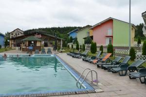 a large swimming pool with lounge chairs next to a building at Vila Hubert in Baile Felix