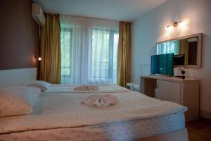 a bedroom with a large bed and a television at Къща за гости Екстаси in Primorsko