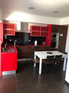 a kitchen with red cabinets and a white table and chairs at Appartement jusqu'à 6 personnes sur la presqu'île de Peniche surf Portugal in Peniche