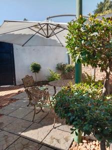 a patio with a bench and an umbrella at 20 On Plover - Private Cottage in Sandton