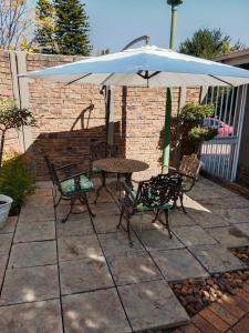 una mesa, sillas y una sombrilla en el patio en 20 On Plover - Private Cottage, en Sandton