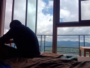 a man sitting on a bed in front of a window at Vaya House in Chiang Mai