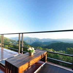 a wooden table on a balcony with a view of mountains at Vaya House in Chiang Mai